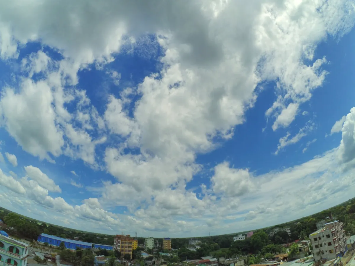 Wide-angle sky full of clouds over a small town